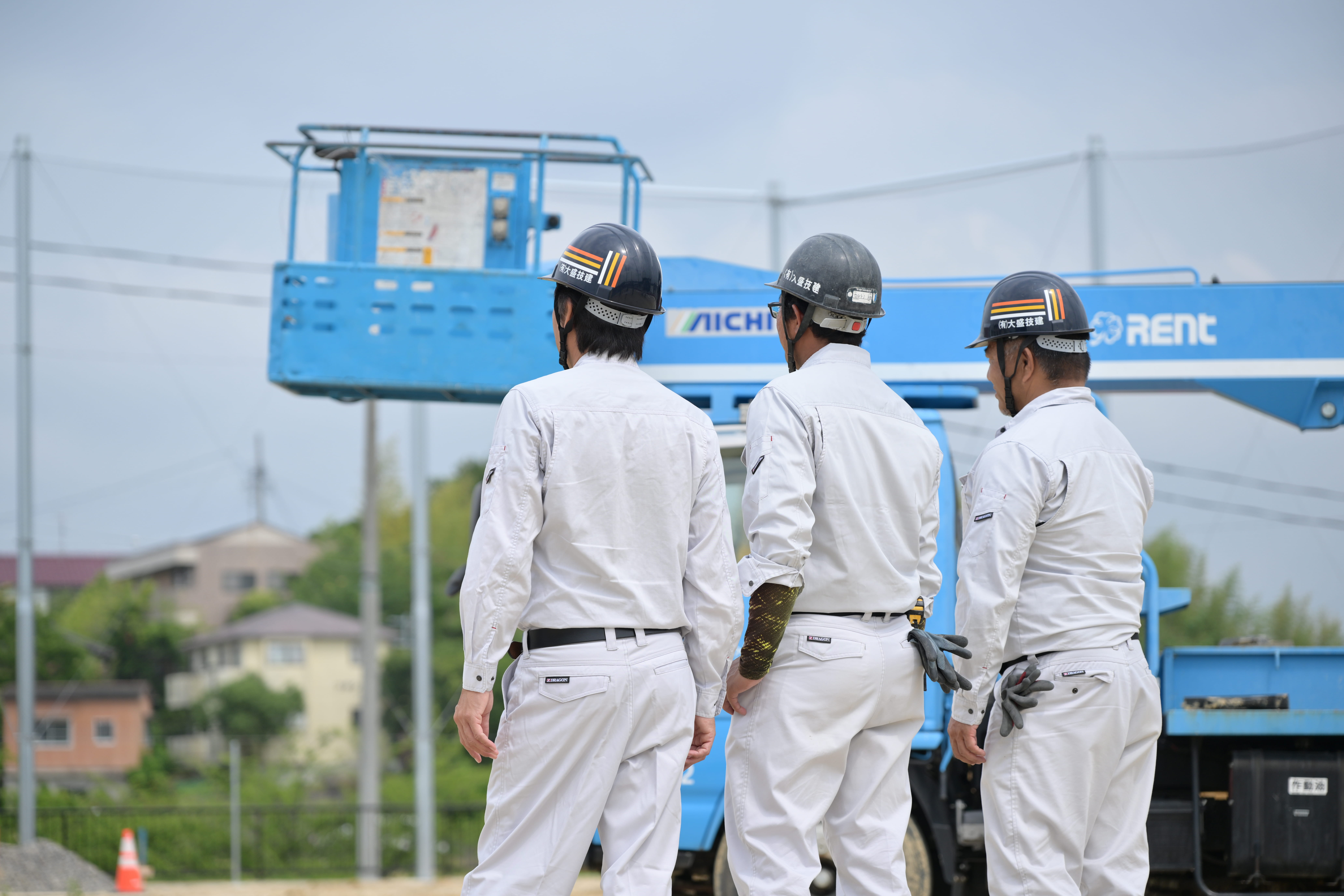 作業着を着てヘルメットを被った男性が3人並んでいる
